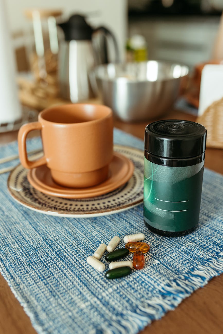 medicine and supplements in capsules on the table next to the cup