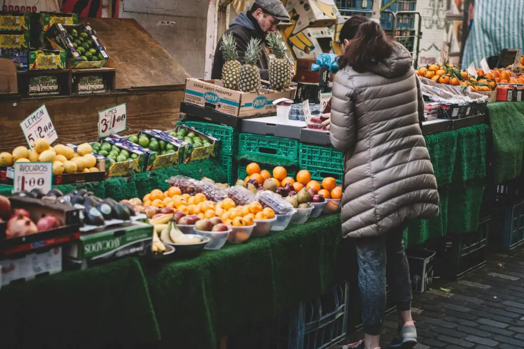 woman standing in front of assorted fruits displayed